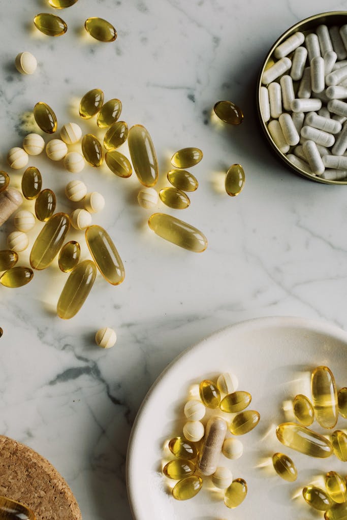 A close-up view of various capsules and pills spread on a marble surface, depicting healthcare concepts.