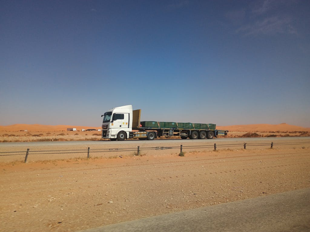 Flatbed truck on a desert highway in Eastern Province, Saudi Arabia under a clear sky.